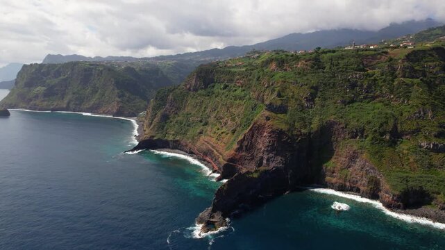 Sao Jorge ruins Madeira island Portugal 4K. Aerial drone panning shot left to right of wild rocky coastline with crashing ocean waves and distant mountain clouds. Remote nature travel stock video