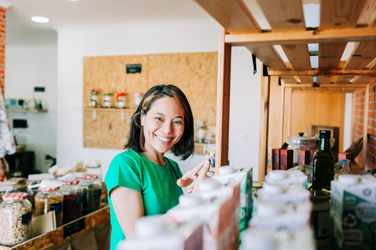 Proud entrepreneur holding a jar in her eco friendly grocery store