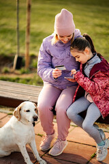Fototapeta premium Mother and daughter using credit card for online shopping in park