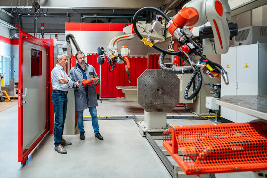 Manager and engineer inspect industrial robot in a modern factory