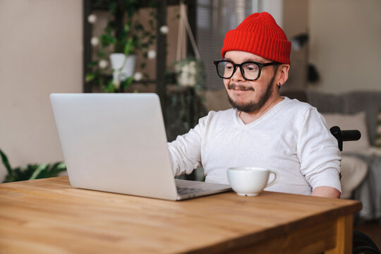 Man with disability wearing knit hat using laptop at home