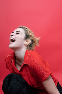 Laughing young woman lin front of red background