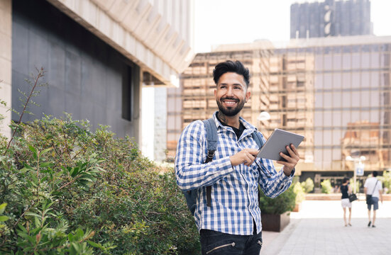 Smiling handsome man holding digital tablet in city