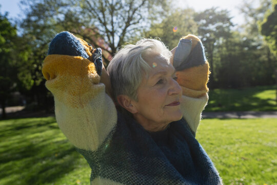 Happy senior woman stretching outdoors in a sunny park