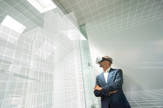 Businessman weraing VR goggles, looking at virtual architcture