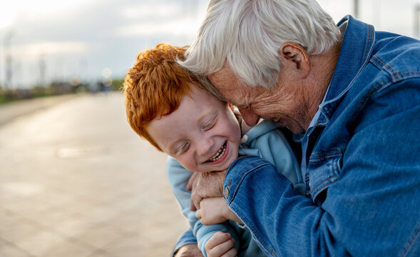 Smiling grandfather embracing grandson in park