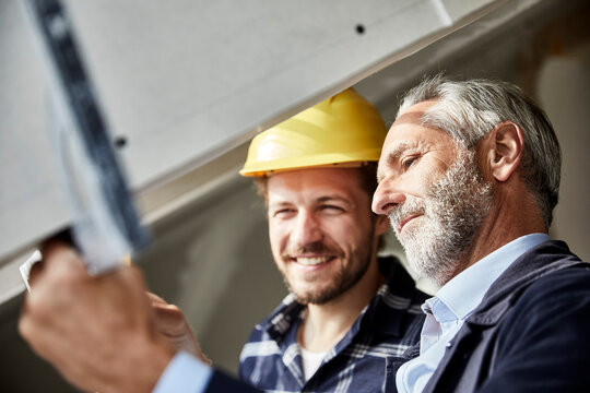 Architect and worker measuring window on a construction site