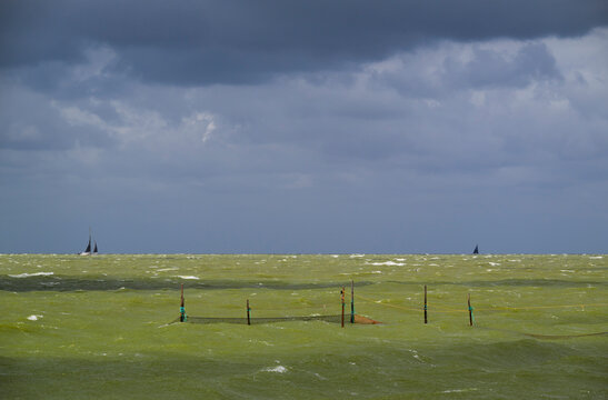 Stormy clouds loom over a fishing net in the choppy IJsselmeer