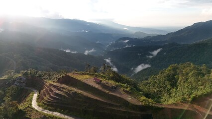 Aerial View of Sunrise Over Misty Tropical Mountain Valley with Terraced Hillside Landscape © Alsy