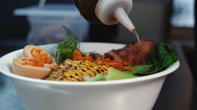 Pouring Chili Sauce over Ramen with Squeeze Bottle