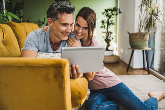 Smiling couple using tablet PC at home