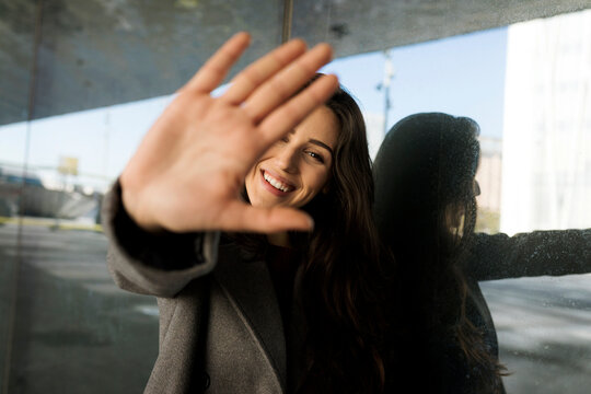 Woman showing stop sign in front of glass wall