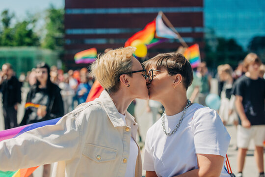 Lesbian couple kissing each other at gay pride event on sunny day