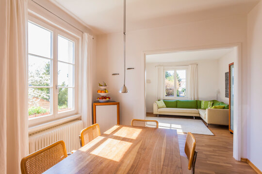 Bright dining room with walnut table leads to a modern living room