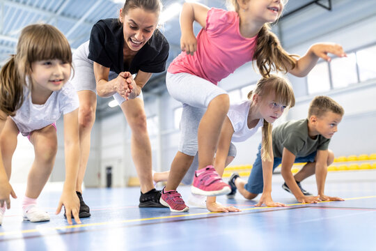Girl starting race with friends by teacher cheering in background