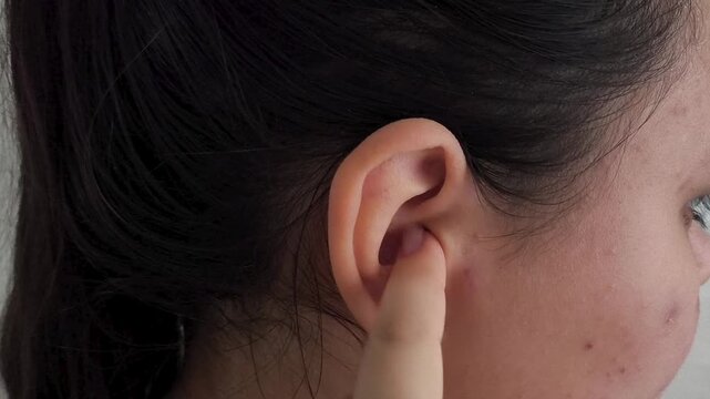 Close up of woman cleaning outer ear with finger, itchy ear, personal hygiene and ENT healthcare concept.