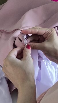 Professional seamstress removing stitches from fabric with seam ripper, garment alteration, dressmaking and textile production concept.