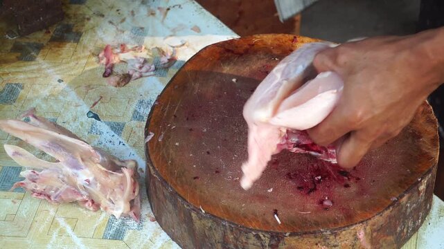 Close Up of Butcher Filleting Raw Chicken Breast on Wooden Chopping Board
