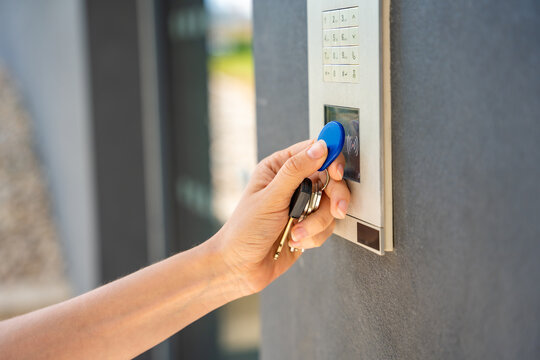 Person using contactless key fob on residential building access control system. Secure entry technology supports convenient and controlled property access