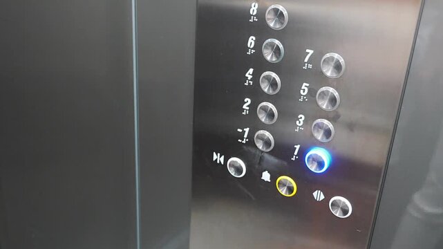 Person pressing the first floor button inside a modern residential elevator. Everyday elevator use supports convenient access and efficient movement between building levels