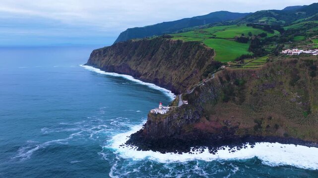 Farol Do Arnel Lighthouse On The Steep Coastal Cliffs Of Sao Miguel Island In The Azores, Portugal. - aerial shot