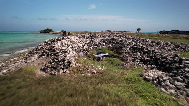 Low-altitude drone flyover of large conch sea shell piles on a remote Caribbean cay in Los Roques Archipelago, Venezuela