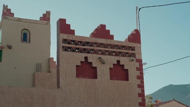 Earthen Moroccan building facade with red geometric Berber patterns and crenellated roofline