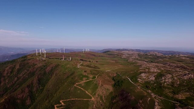 Wind turbines line green mountain ridge with trails and rocky terrain at Serra da Freita in Arouca Portugal