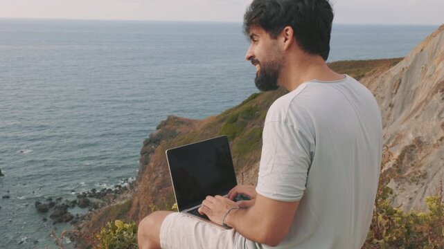 Remote worker finishing work and dreaming of adventure on a cliff