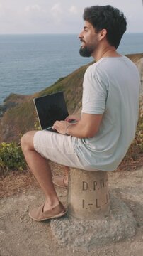 vertical Digital nomad working remotely on a laptop with a stunning ocean view