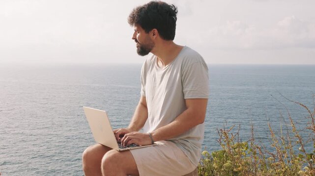 Digital nomad working remotely on a laptop with an ocean view