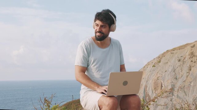 Digital nomad working remotely on laptop at scenic cliffside viewpoint