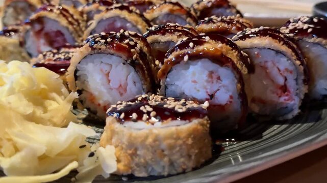 Assorted fried sushi rolls with white pickled ginger on restaurant table, Japanese cuisine platter presented for sharing and gourmet dining experience