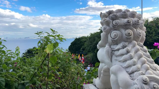 Da nang, lady buddha, white foo dog statue guarding ancient temple grounds overlooking a scenic mountain ocean bay with distant city skyline