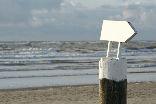Blank white sign by the beach on an overcast day