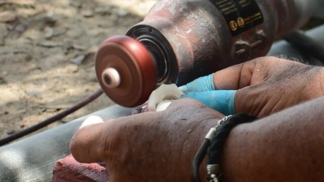 Authentic craftsmanship workshop.Traditional handmade production, precision finishing, and artisan techniques polishing a handcrafted seashell using rotating bench grinder. 4K D-Log ungraded footage.
