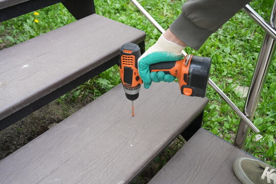 Drilling composite decking step with orange cordless drill outdoors