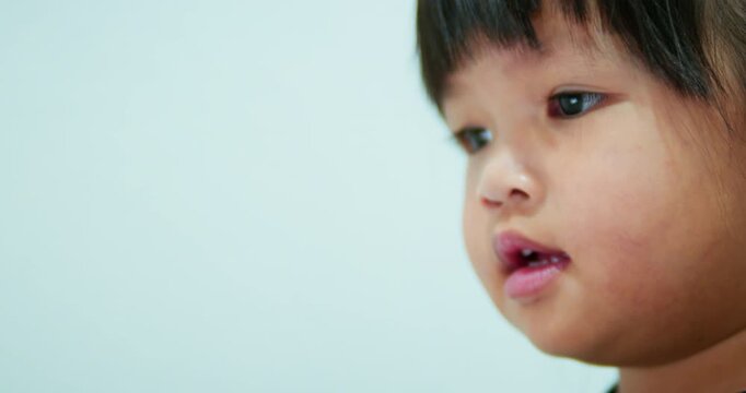 Candid authentic lifestyle shot of a young toddler focused on a touchscreen device. The little girl is learning and playing through an educational application indoors.
