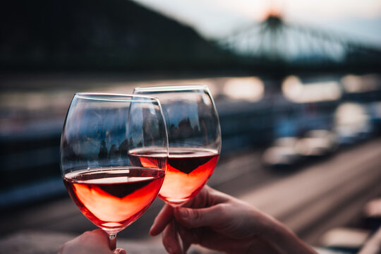 Hand holding glasses of rose wine in summer sunshine during a outdoors party or a picnic.