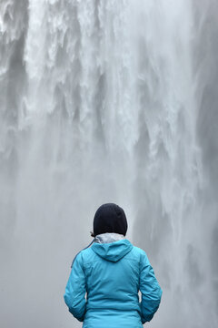 Hiker standing before the immense Skogafoss waterfall, Iceland