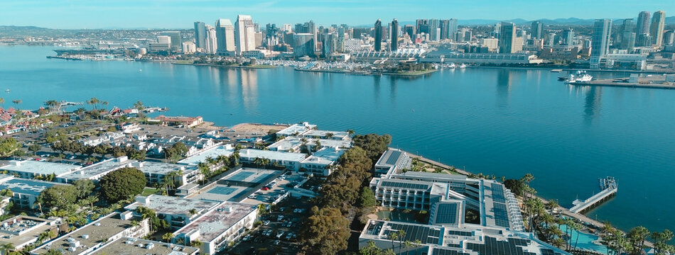 Solar paneled lodging structures overlook calm bayfront docks while metropolitan glass towers dominate northern horizon. Prime location elevates travel experiences throughout Coronado, CA