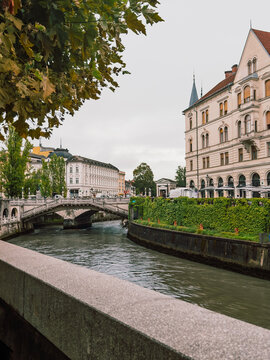 Historic Triple Bridge crossing the Ljubljanica River in Ljubljana, Slovenia, surrounded by elegant architecture and riverside streets on a cloudy day