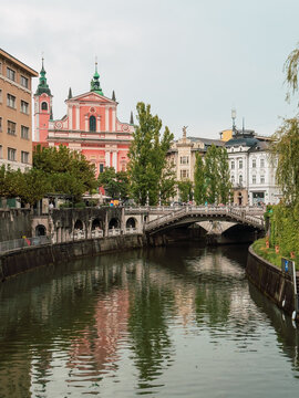 A picturesque view of the Ljubljanica River flowing through the heart of Ljubljana, Slovenia, with iconic architecture lining its banks