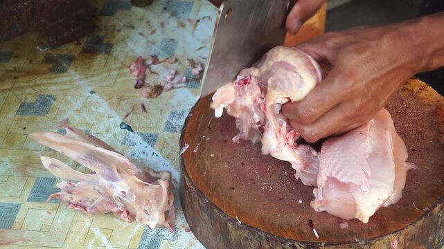 Close Up of Butcher Filleting Raw Chicken Breast on Wooden Chopping Board