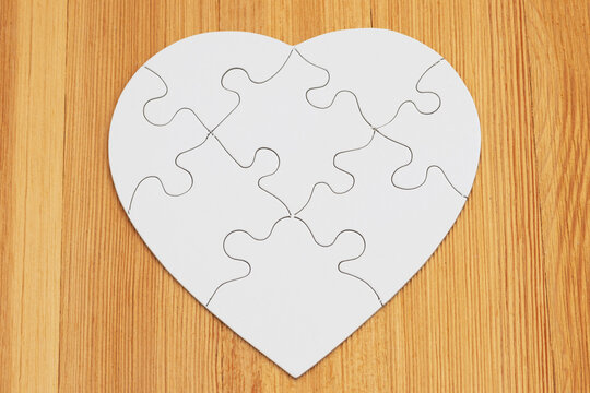 Blank white puzzle heart on wood for partnership
