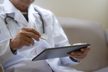Healthcare professional using a digital tablet with a stylus to review patient information and medical records. Ideal for electronic health records, telemedicine, and digital healthcare concepts. © Teelapon