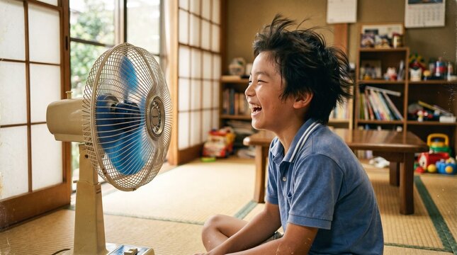 昭和の日本人小学生：和室の扇風機の前で大きな口を開けて風を浴び、楽しそうに涼む日本人小学生男子の夏休みクローズアップポートレート