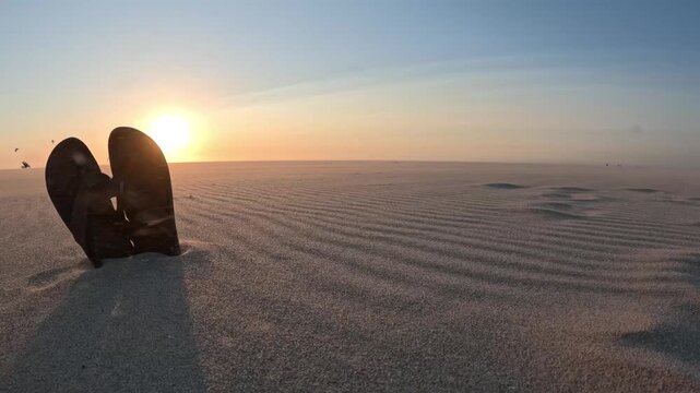 Relaxing Dutch beach atmosphere with flip-flops, glowing evening light and distant kitesurfers
