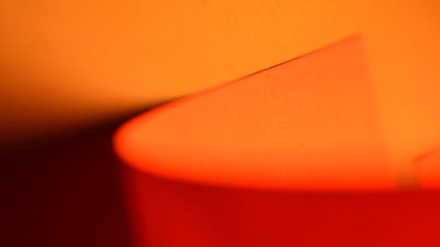 Warm orange and red abstract paper sculpture with soft glowing curves . 