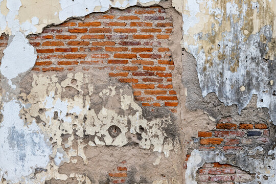 A weathered and distressed background of an old brick wall with peeling white plaster, exposed red bricks, and rough concrete patches, ideal for architectural design, rustic backdrops, and 3D